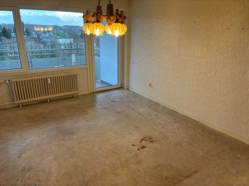 Geräumiger leerer Raum mit einem Fenster und einem Kronleuchter an der Decke.