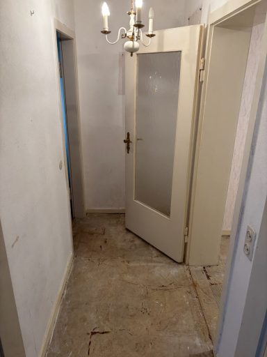 Ein einfacher Flur mit offenen Türen und unebenen Bodenflächen.
