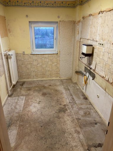 Leere Küche mit freiliegenden Wänden und unebenen Bodenflächen.