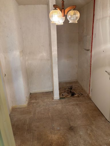 Leerer Raum mit einem weißen Boden, einer Säule und einer Deckenlampe.